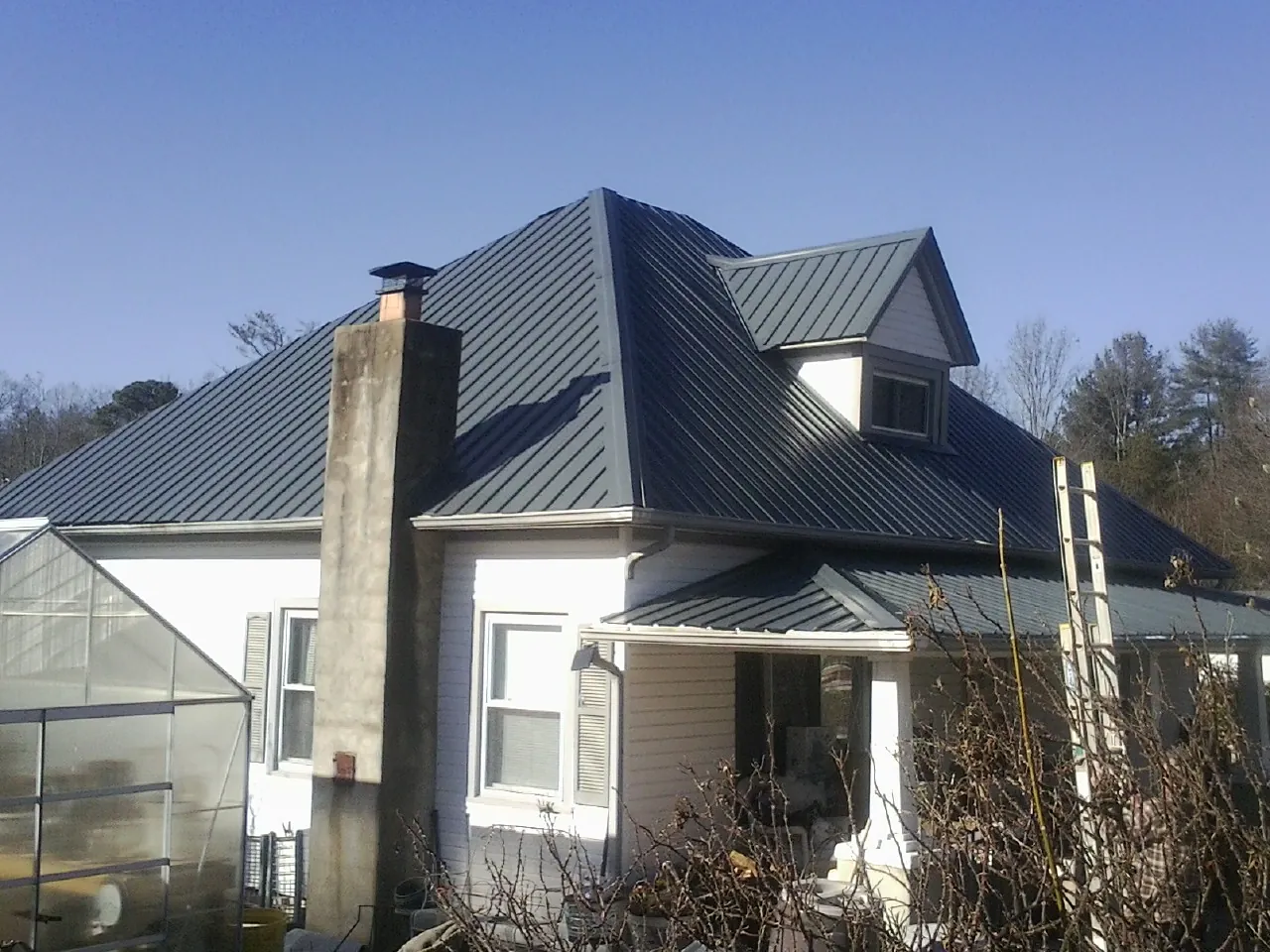 Dark blue standing seam metal roof on a white farmhouse with dormer — Slate & Tile Roof Repair by Roofing Brothers in Long Grove