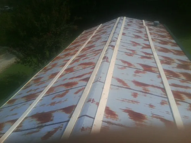 Rusted metal roof panels with new wood purlins before replacement — Storm Damage Roof Repair in Long Grove by Roofing Brothers