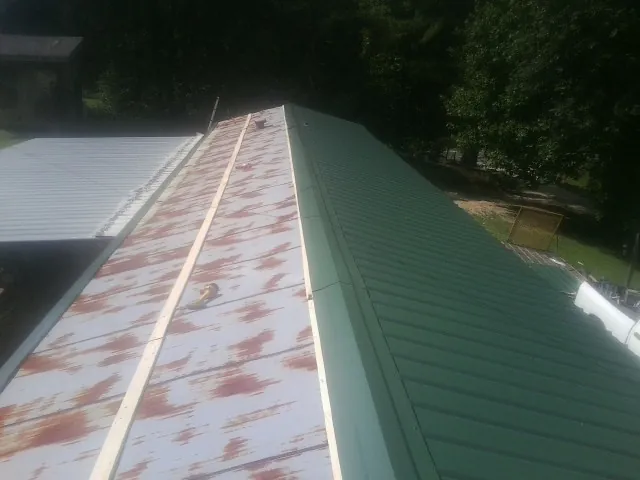 Old rusted panels beside newly installed green metal roofing — Wind Damage Roof Repair by Roofing Brothers in Long Grove