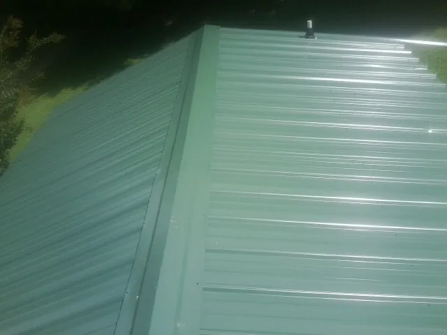 New green metal panels meeting at the ridge of a roof — Flat Roof Repair work by our crew in Long Grove