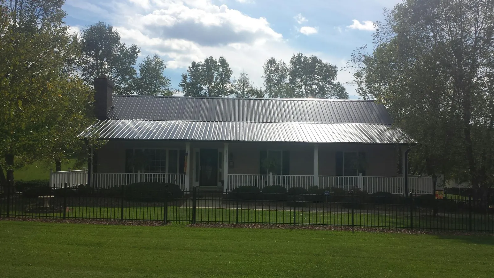 Gray metal roof on a brick ranch with a full width front porch — Gutter Guard Installation work by our crew in Long Grove