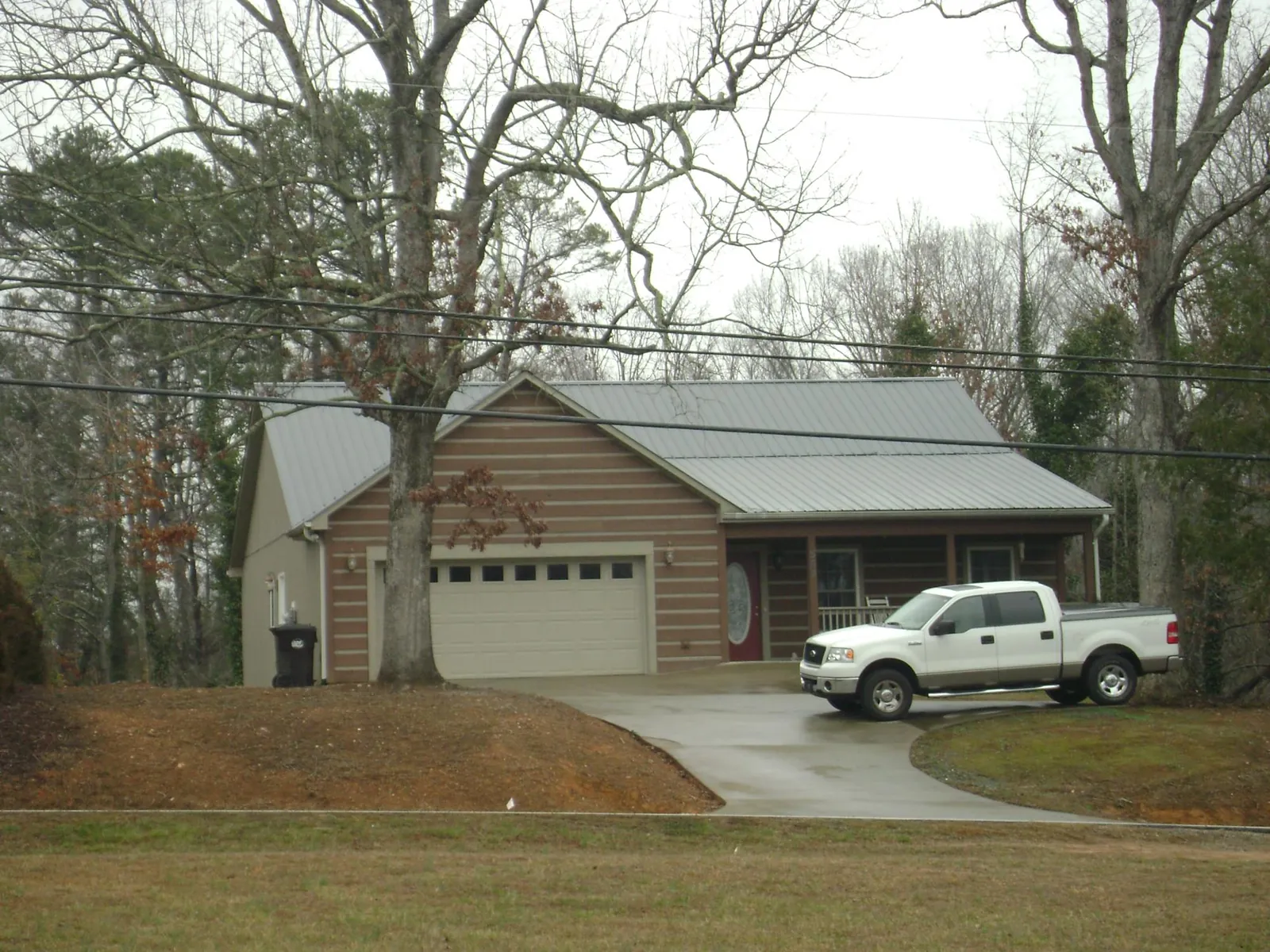 Gray metal roof on a log sided house with an attached two car garage in Long Grove