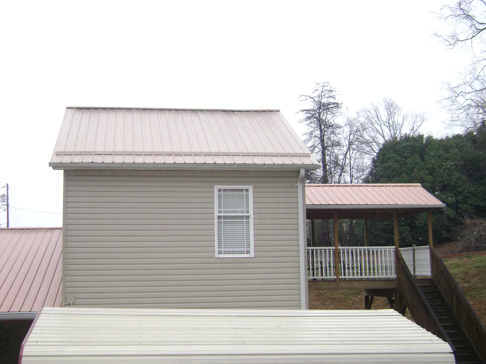 Tan metal roofs on a two story addition and attached porch, from a Roof Replacement job in Long Grove