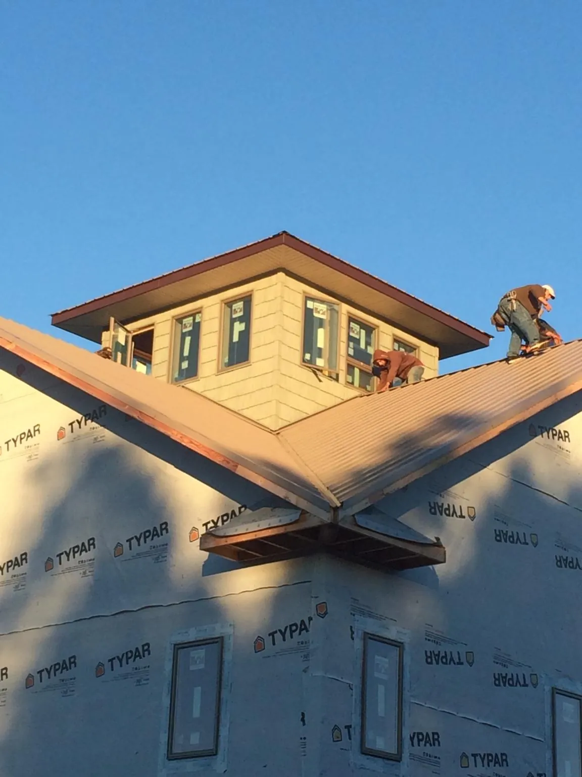 Roofers working around a rooftop cupola on a new metal roof at sunset — Roof Waterproofing in Long Grove by Roofing Brothers